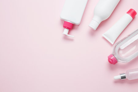 Cosmetic beauty products on pink background. Bottles and tubes with branding mock up. Skin care and beauty concept. Top view, flat lay, copy spaceの写真素材