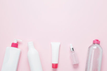 Cosmetic beauty products on pink background. Bottles and tubes with branding mock up. Skin care and beauty concept. Top view, flat lay, copy spaceの写真素材