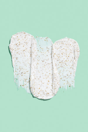 Smears of body scrub on green background. Fruit and berry body scrub texture of the swatch. Cosmetic...