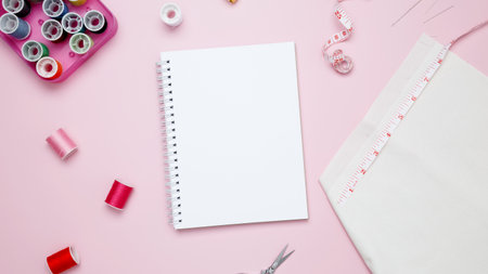 Composition with various threads and sewing accessories on pink background. Mock up notebook