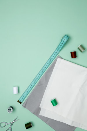 Composition with various threads and sewing accessories on green background. Top view, copy space
