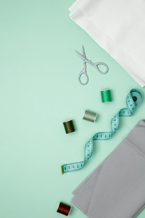 Composition with various threads and sewing accessories on green background. Top view, copy space