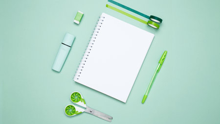 Creative flat lay mockup design of workspace. Top view composition with white notebook, to do list and stationery on green backgroundの写真素材