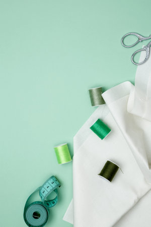 Composition with various threads and sewing accessories on green background. Top view, copy spaceの写真素材
