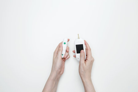 Female hands holding glucometer for measuring blood glucose levels and lancet. Concept of worldwide...