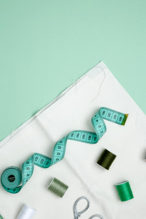 Composition with various threads and sewing accessories on green background. Top view, copy space