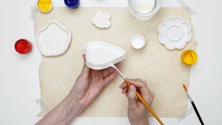 A woman paints clay products. Hobby clay modeling