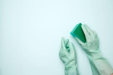 Womans hand in rubber glove holds dishwashing sponge. House cleaning. Copy spaceの写真素材