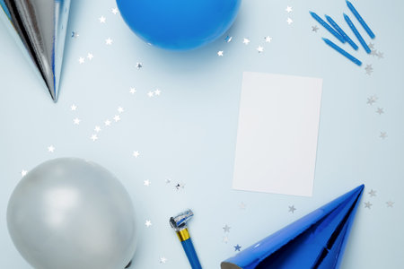 Blank card surrounded by colorful balloons, party hats, candles, and confetti. Concept of festive birthday celebrationsの写真素材