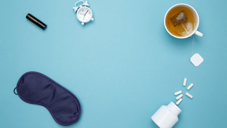 Sleep essentials eye mask, tea, pills, clock. Concept of relaxation and rest, insomnia treatmentの写真素材