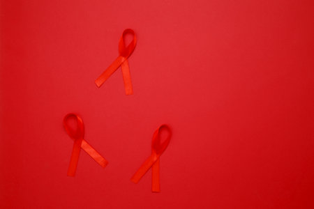 Red ribbons with awareness about AIDS on a red background. World AIDS Day
