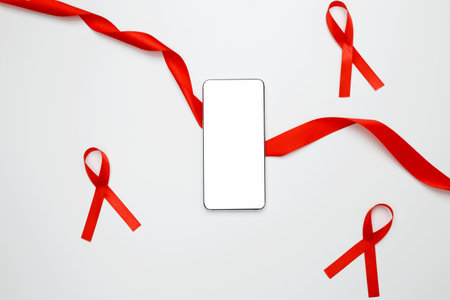 Red ribbon with AIDS awareness on a white background and a smartphone for mock up. World AIDS Day