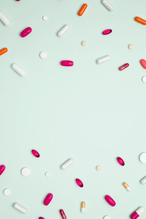 Various colorful pills and capsules scattered on a light blue background. Concept of medicine, healthcare, and pharmaceutical industryの写真素材