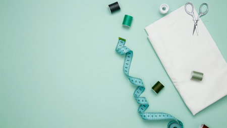 Composition with various threads and sewing accessories on green background. Top view
