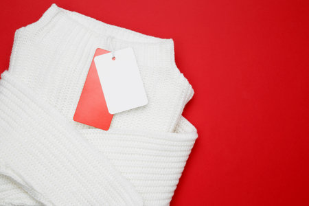 White sweater with a white tag against a red background, symbolizing holiday shopping vibesの写真素材