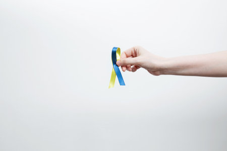 A person holds a yellow and blue awareness ribbon, symbolizing World Down Syndrome Day