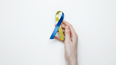 Symbolizing World Down Syndrome Day. A person holds a yellow and blue awareness ribbonの写真素材