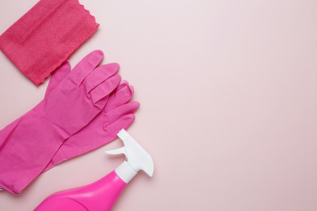 Pink cleaning supplies including rubber gloves, spray bottle, microfiber cloths. Household cleaning...