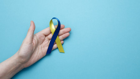 Symbolizing World Down Syndrome Day. A person holds a yellow and blue awareness ribbonの写真素材