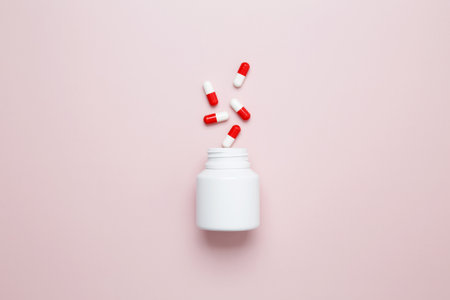 White bottle container with colorful medication capsules and tablets. Concept of healthcare and medicineの写真素材