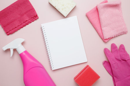 Pink cleaning supplies including rubber gloves, spray bottle, microfiber cloths. Household cleaning and hygiene concept. Mock up notebookの写真素材