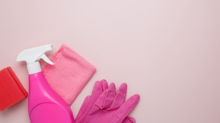 Household cleaning and hygiene concept. Pink cleaning supplies including rubber gloves, spray bottle, sponge, and microfiber clothsの写真素材