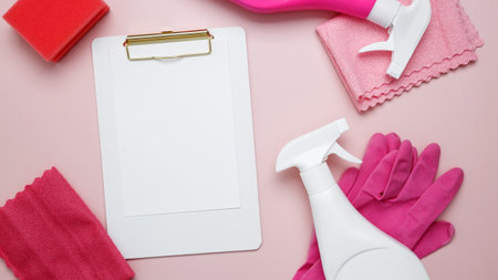 Mock up clipboard. Household cleaning and hygiene concept. Pink cleaning supplies including rubber gloves, spray bottle, microfiber clothsの写真素材
