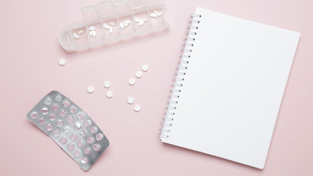 Concept of medicine, healthcare, and pharmaceutical industry. Blister of tablets and blank notebookの写真素材