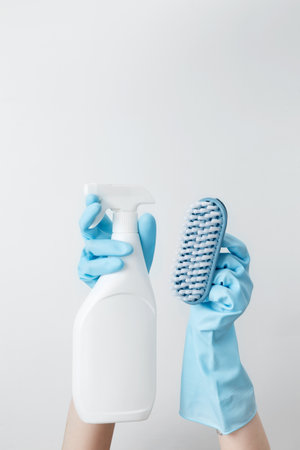 Woman in rubber gloves holding cleaning spray and brush, ready for household cleaning tasksの写真素材