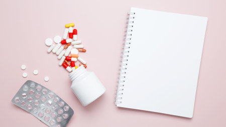 Concept of medicine, healthcare, and pharmaceutical industry. White bottle container with colorful medication capsules and mock up notebookの写真素材