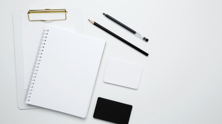 Monochrome stationery items. On a white background, an empty mock up notebook and clipboard, white and black cardsの写真素材
