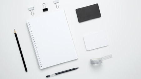 Monochrome stationery items. On a white background, an empty mock up notebook, white and black cardsの写真素材