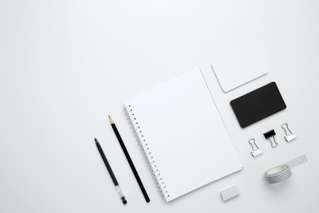On a white background, an empty mock up notebook, white and black cards, monochrome stationery items arranged neatlyの写真素材
