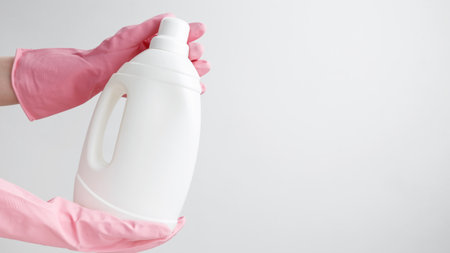 Household cleaning and hygiene concept packaging. Female hand in a pink rubber glove holding a white...