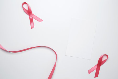 Pink ribbons on white card for breast cancer awareness and prevention reminder
