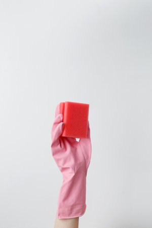 Hand in pink rubber glove holding a sponge for cleaning. Household cleaning and hygiene conceptの写真素材