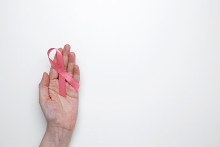 Female hand holding pink ribbon symbol of breast cancer awarenessの写真素材