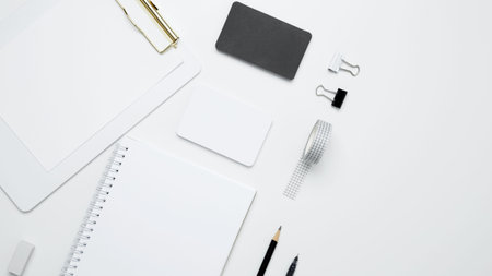 On a white background, an empty mock up notebook and clipboard, white and black cards. Monochrome...