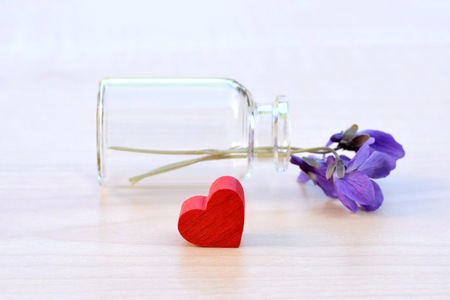 Wooden red heart with viola odorata flower in a glass vialの写真素材