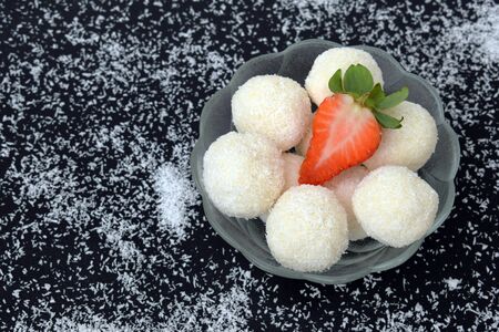 Unbaked homemade coconut balls decorated with strawberry