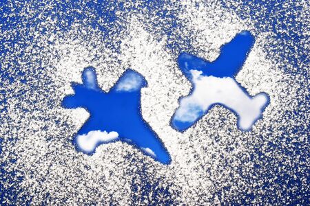 Creative composition of two airplanes and blue sky with clouds inside, sugar sprinkled backgroundの写真素材