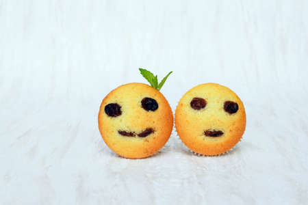 Freshly baked homemade muffins with funny faces. Vanilla muffins with raisins, decorated with...