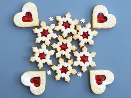 Homemade linzer cookies filled with strawberry jam, small sugar snowflakes around. Blue-gray...