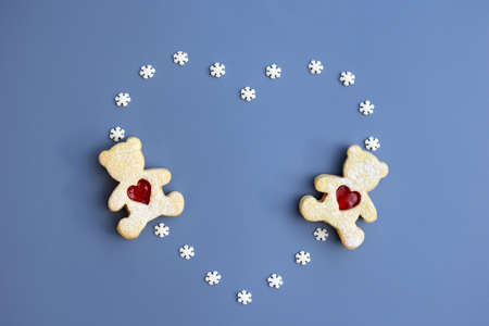 Linzer cookies in a shape of bears with heart and heart created from small sugar snowflakes on blue