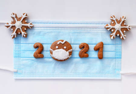 Gingerbread numbers 2021 and snowflakes on protective face mask - creative New year concept in...