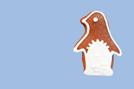 Cute gingerbread penguin decorated with white icing, isolated on light blue background. Copy space...