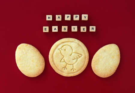 Original Easter concept with butter cookies and HAPPY EASTER text made of wooden cubes, red...