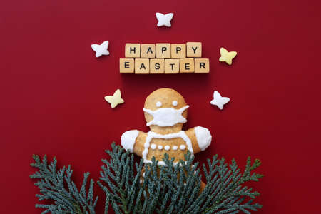 Original Easter concept - cute gingerbread man with protective face mask, HAPPY EASTER text made of...