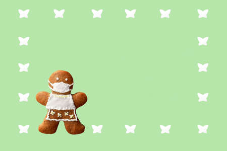 Cute gingerbread woman with protective face mask in a frame from butterflies, isolated, green...