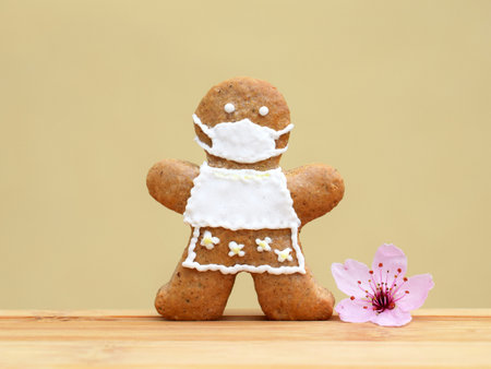 Cute gingerbread woman with protective face mask and tender spring tree blossom.  time, greeting...